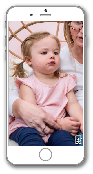 A woman is holding a little girl in her arms on a cell phone.