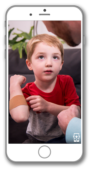 A little boy is sitting on a couch with a bandage on his arm.