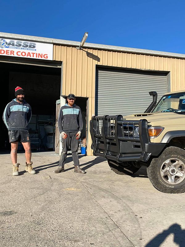 Two Men Are Standing Next to A Truck in Front of A Building — ASSB Armidale Sand & Soda Blasting In  Armidale, NSW