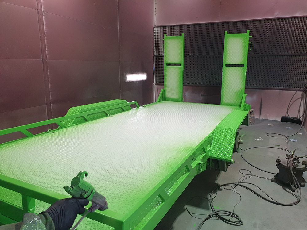 A Green Trailer Is Being Painted in A Paint Booth — ASSB Armidale Sand & Soda Blasting In  Armidale, NSW