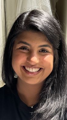A woman with long black hair is smiling for the camera.