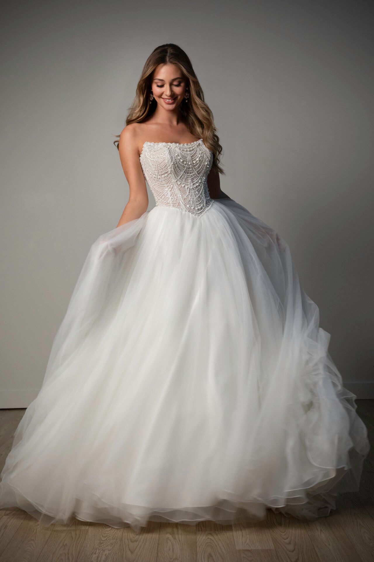 A woman in a white wedding dress is standing on a beach.