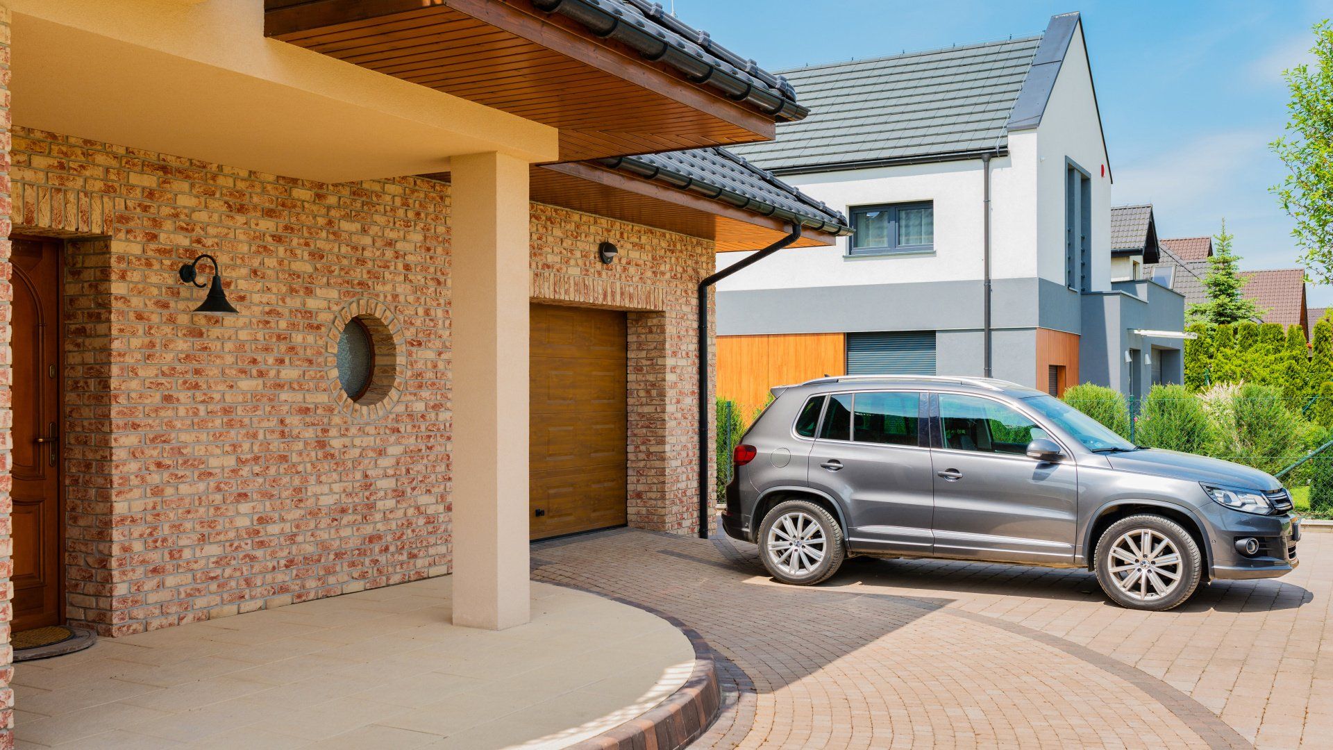 A car is parked in front of a house in a driveway.