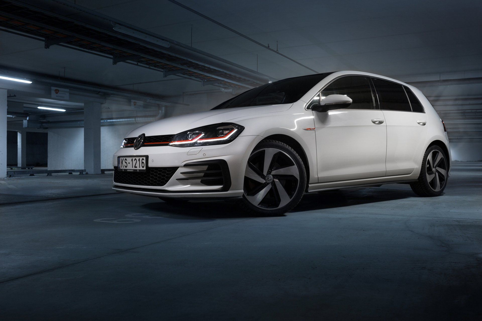 A white volkswagen golf gti is parked in a parking garage.