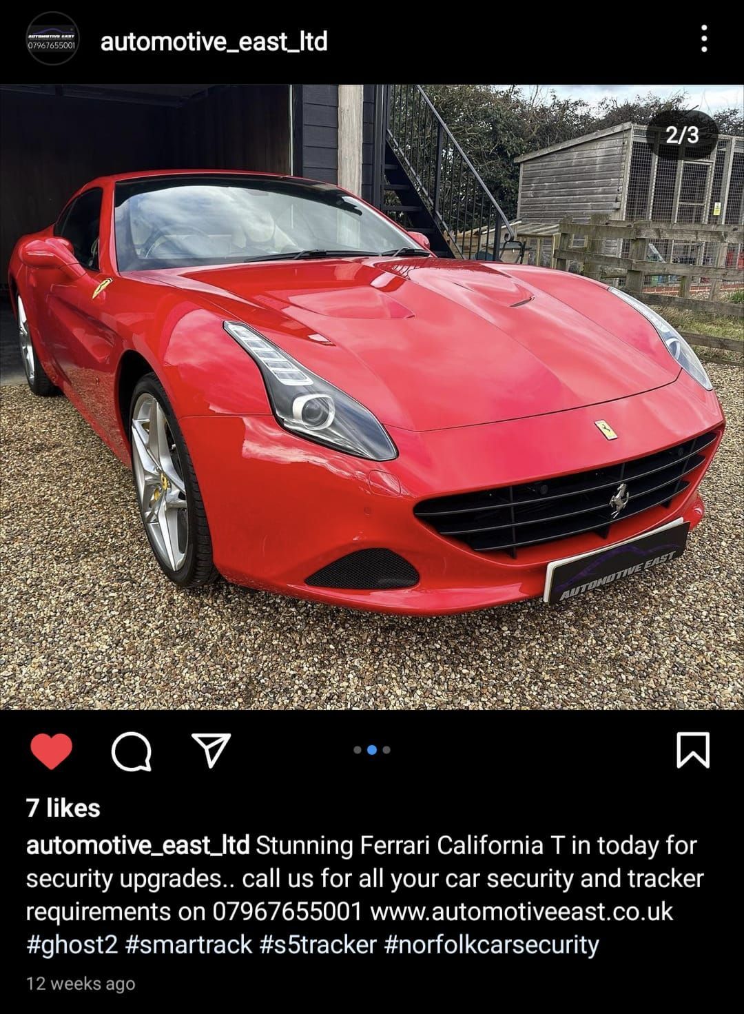 A red ferrari is parked in front of a garage.