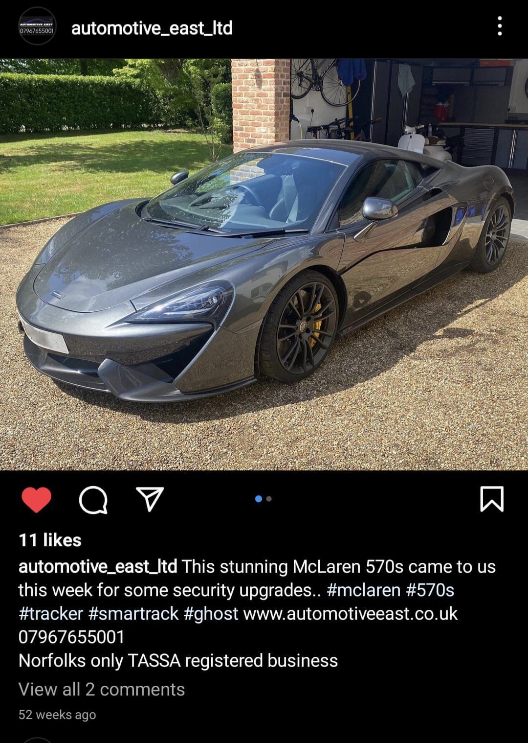 A gray sports car is parked in a driveway next to a garage.