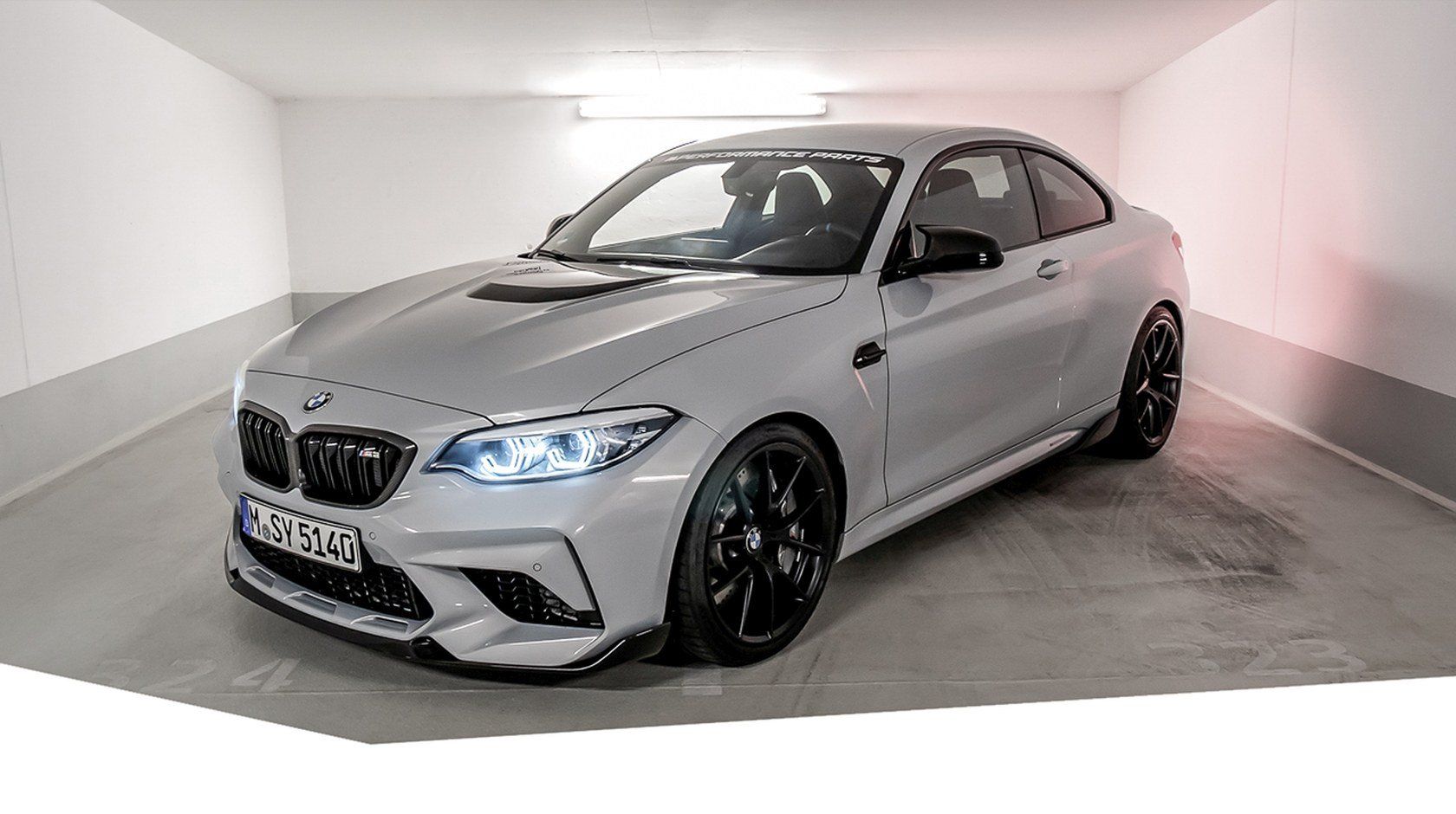 A bmw m2 is parked in a garage.