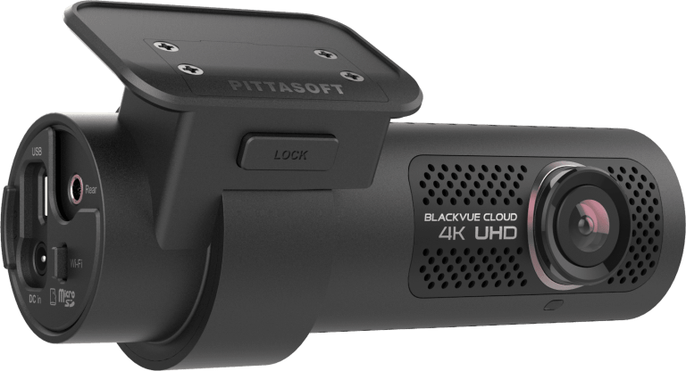 A black 4k uhd dash cam is sitting on a white surface.