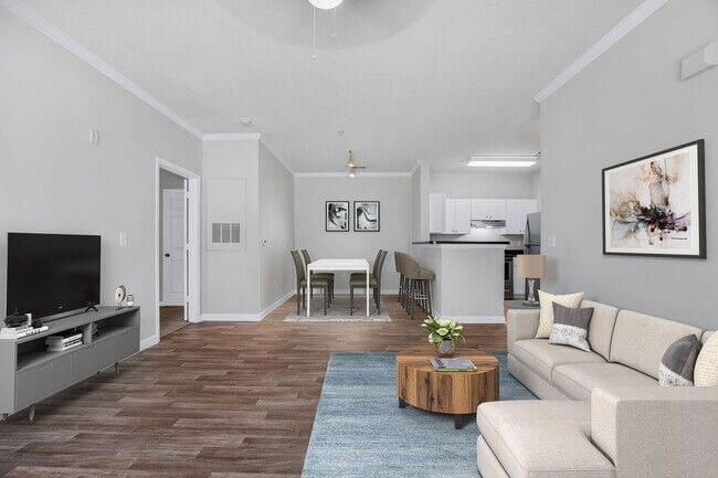 Living room with a sofa, TV, dining table, and open kitchen; neutral tones and wood floors.