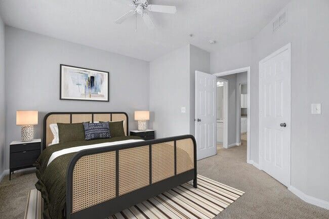 Bedroom with bed, nightstands, and a doorway to the bathroom; light gray walls, neutral colors.