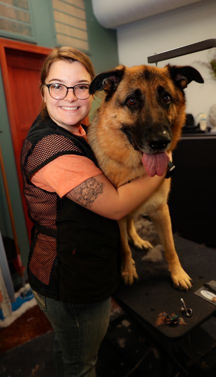 A woman is holding a german shepherd dog in her arms.