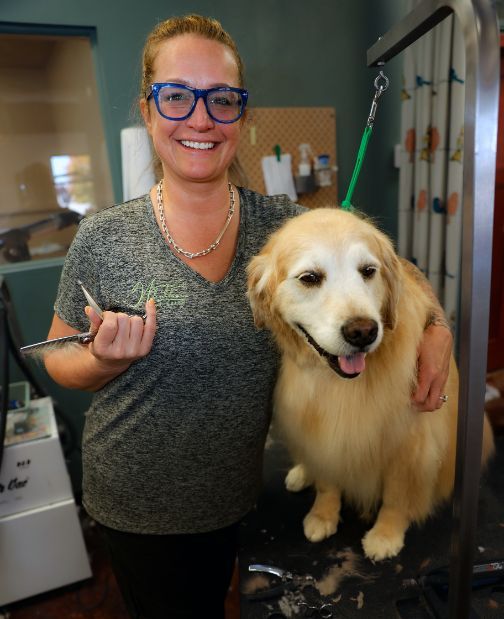 A woman is holding a pair of scissors next to a dog