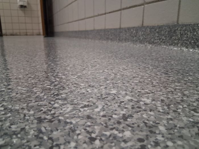Shiny, speckled epoxy floor in a garage with a closed white door and glass garage door.