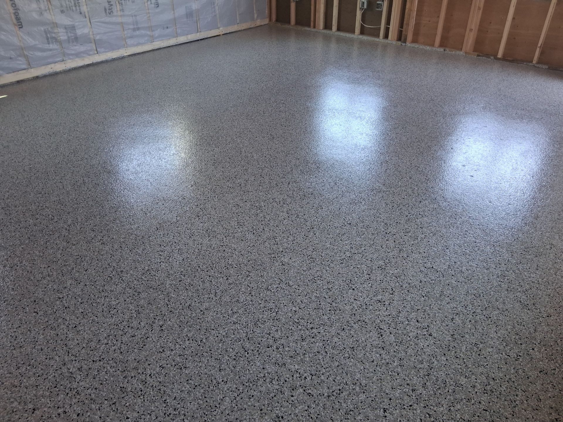 Person sanding a wooden floor with a floor sander in an empty room.