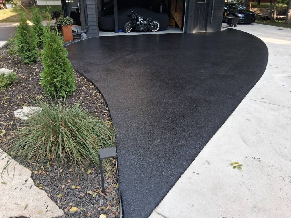 Person staining a wooden floor with a brush, applying brown stain.