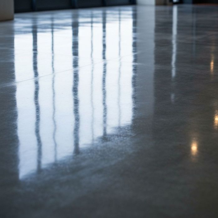 Shiny gray concrete floor reflecting window light.