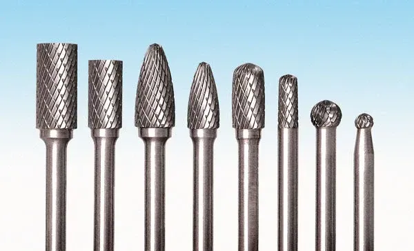 A group of drill bits are lined up in a row on a blue surface.