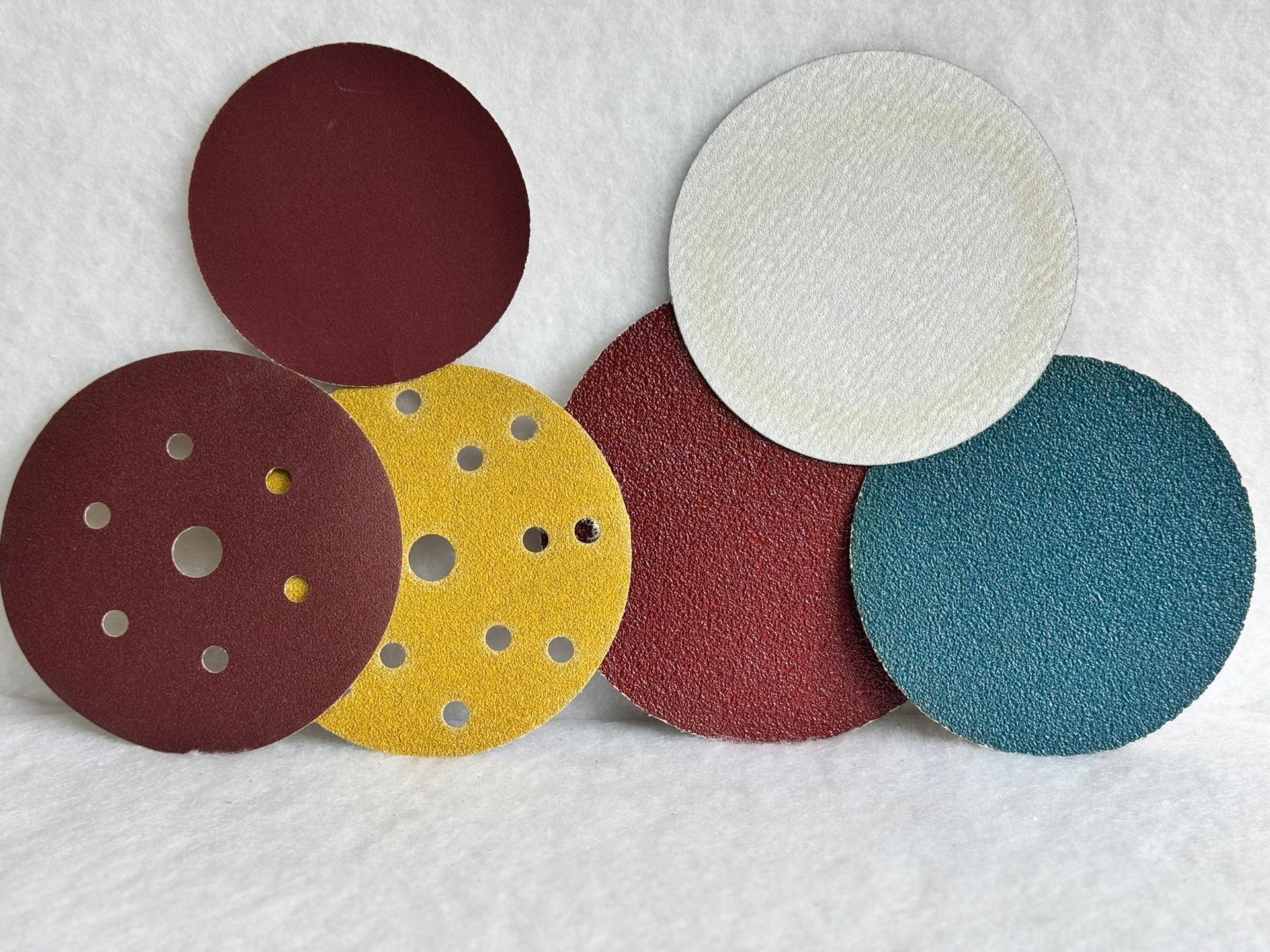 A pair of yellow sanding pads with holes in them on a white background.