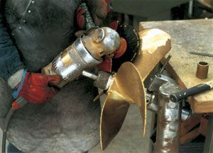 A man is grinding a propeller with a grinder. A man is grinding a propeller with a grinder.