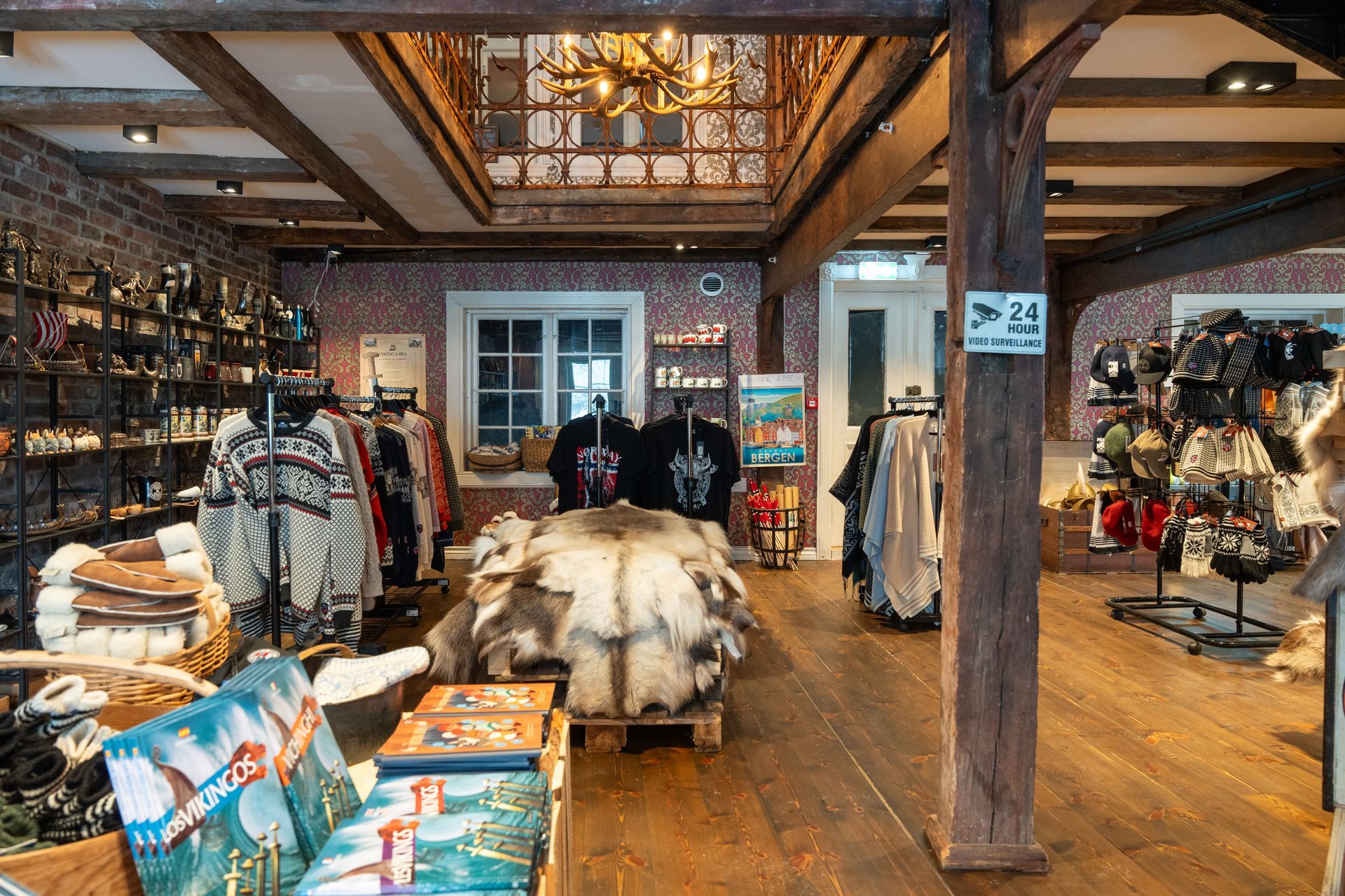 Cozy boutique interior with clothing racks, rustic beams, and display tables under warm lighting, Viking Shop In Bergen