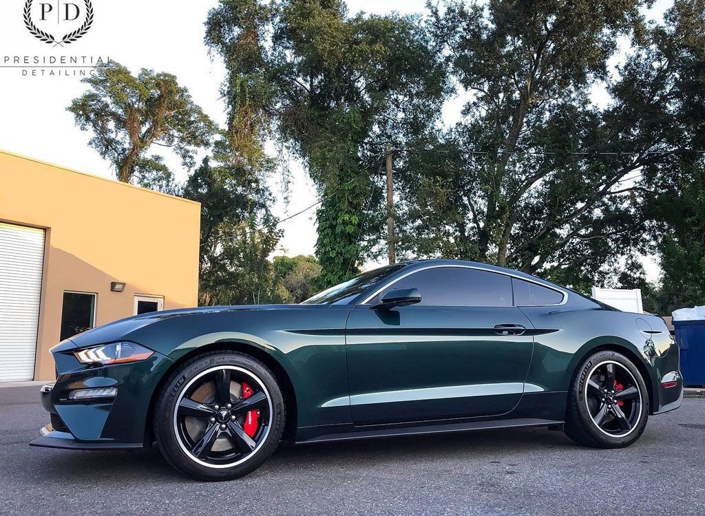 Green Ford Mustang with black wheels and red calipers parked outside.