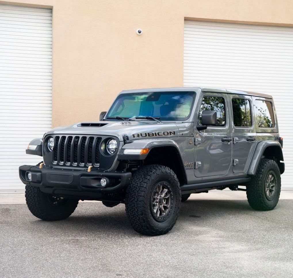 a jeep rubicon is parked in front of a garage