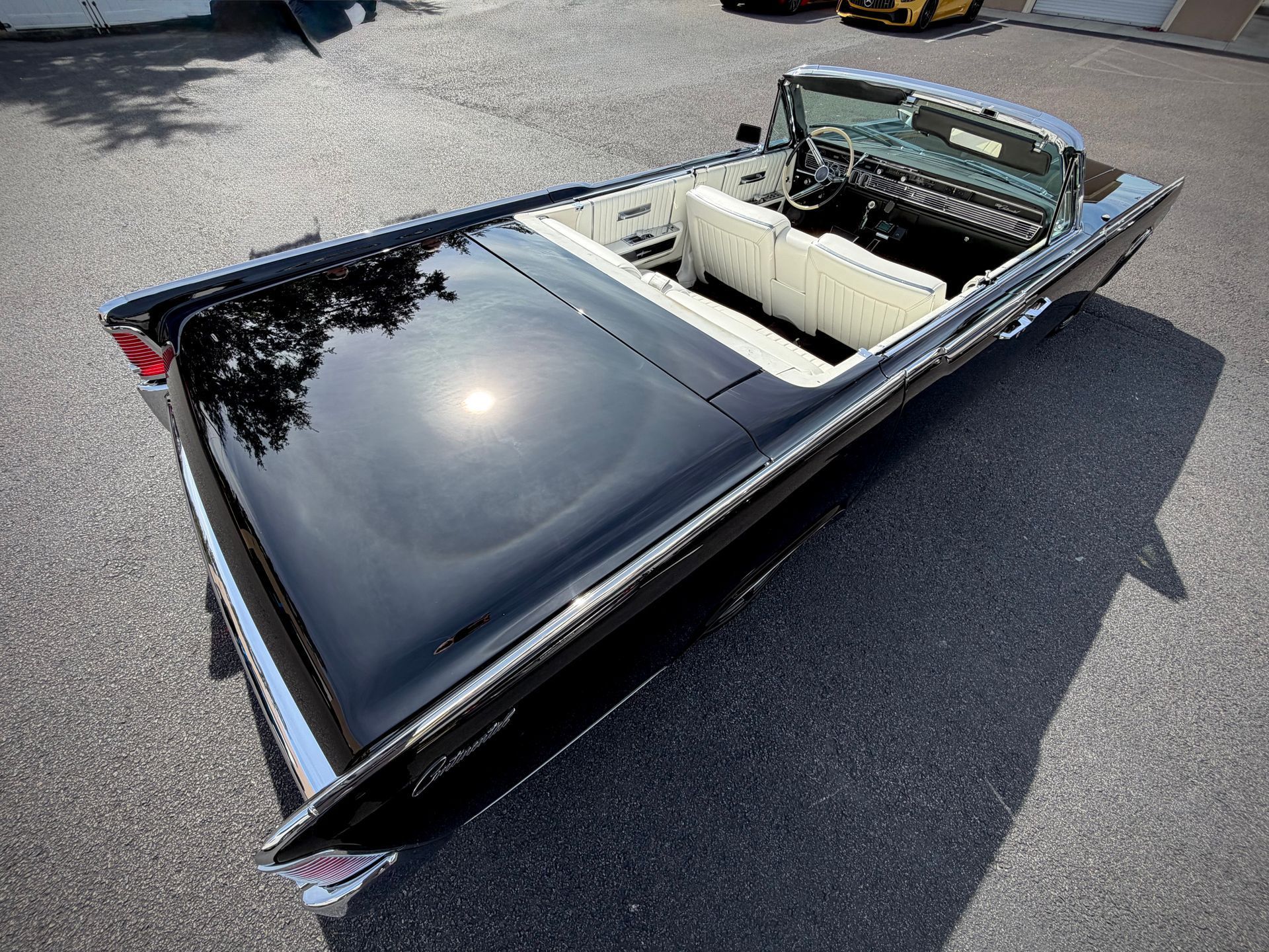 Black convertible car with white interior parked on asphalt.