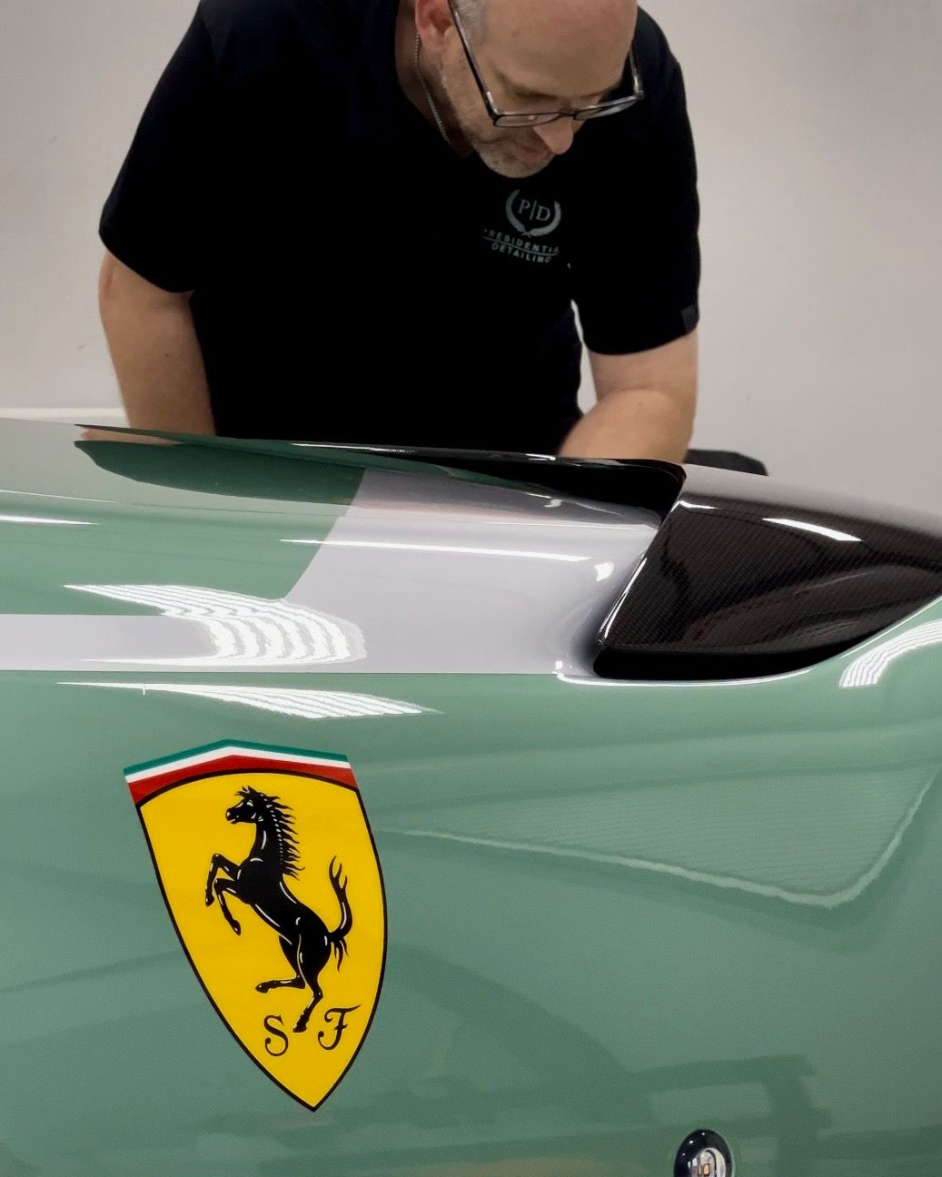 A man is working on a green ferrari car