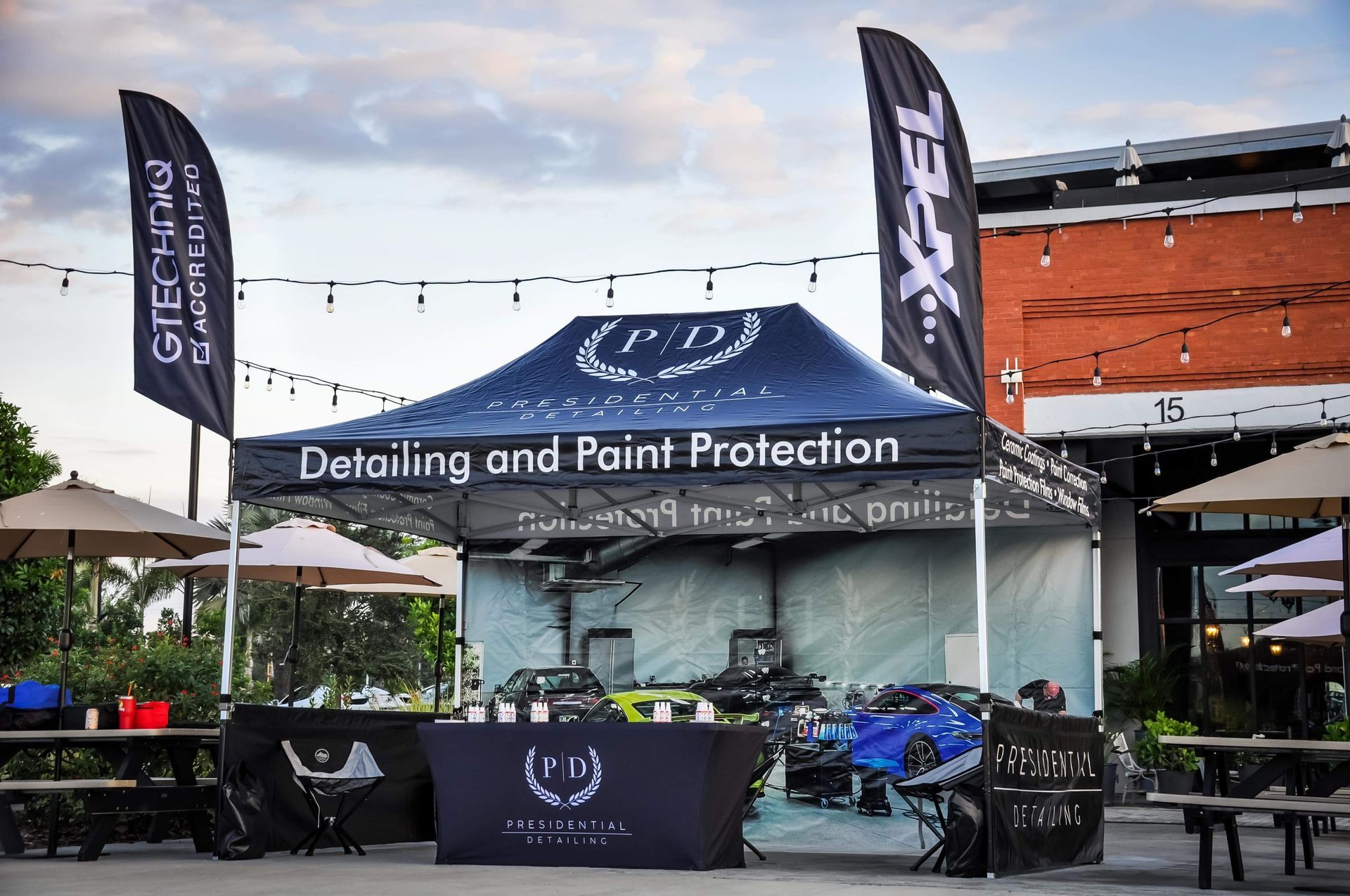 Outdoor car detailing tent with cars, tables, and flags
