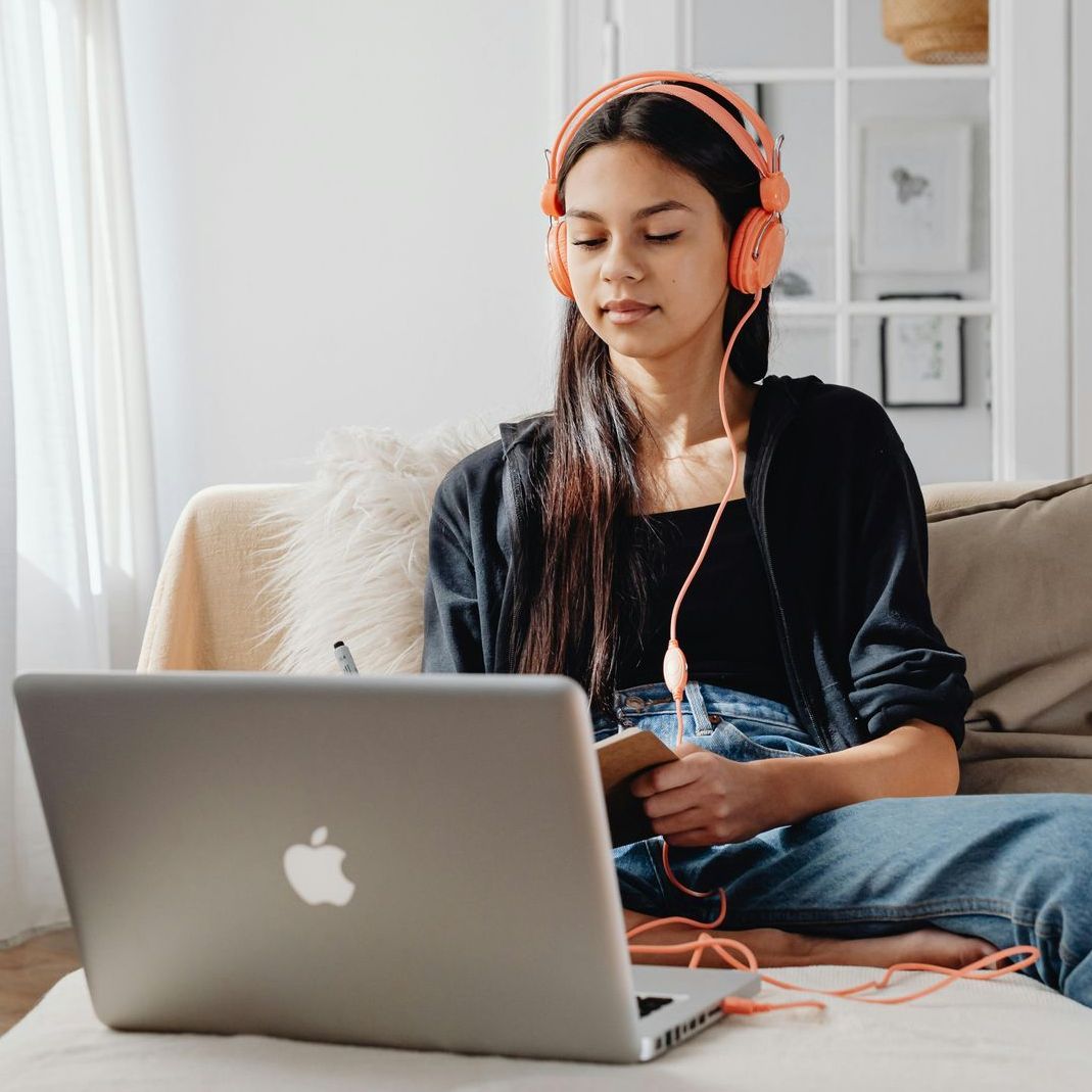 A woman wearing glasses and headphones is sitting at a desk.