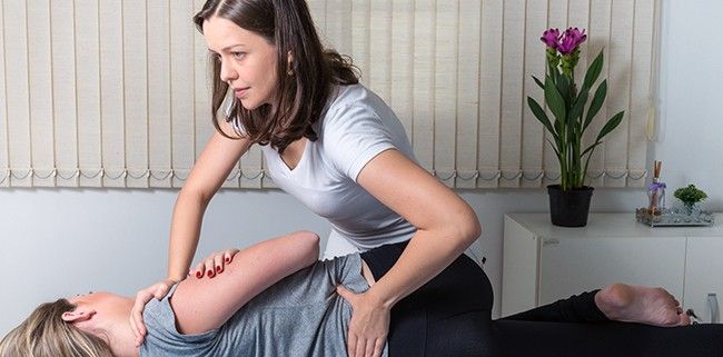 Woman Chiropractor adjusts patient