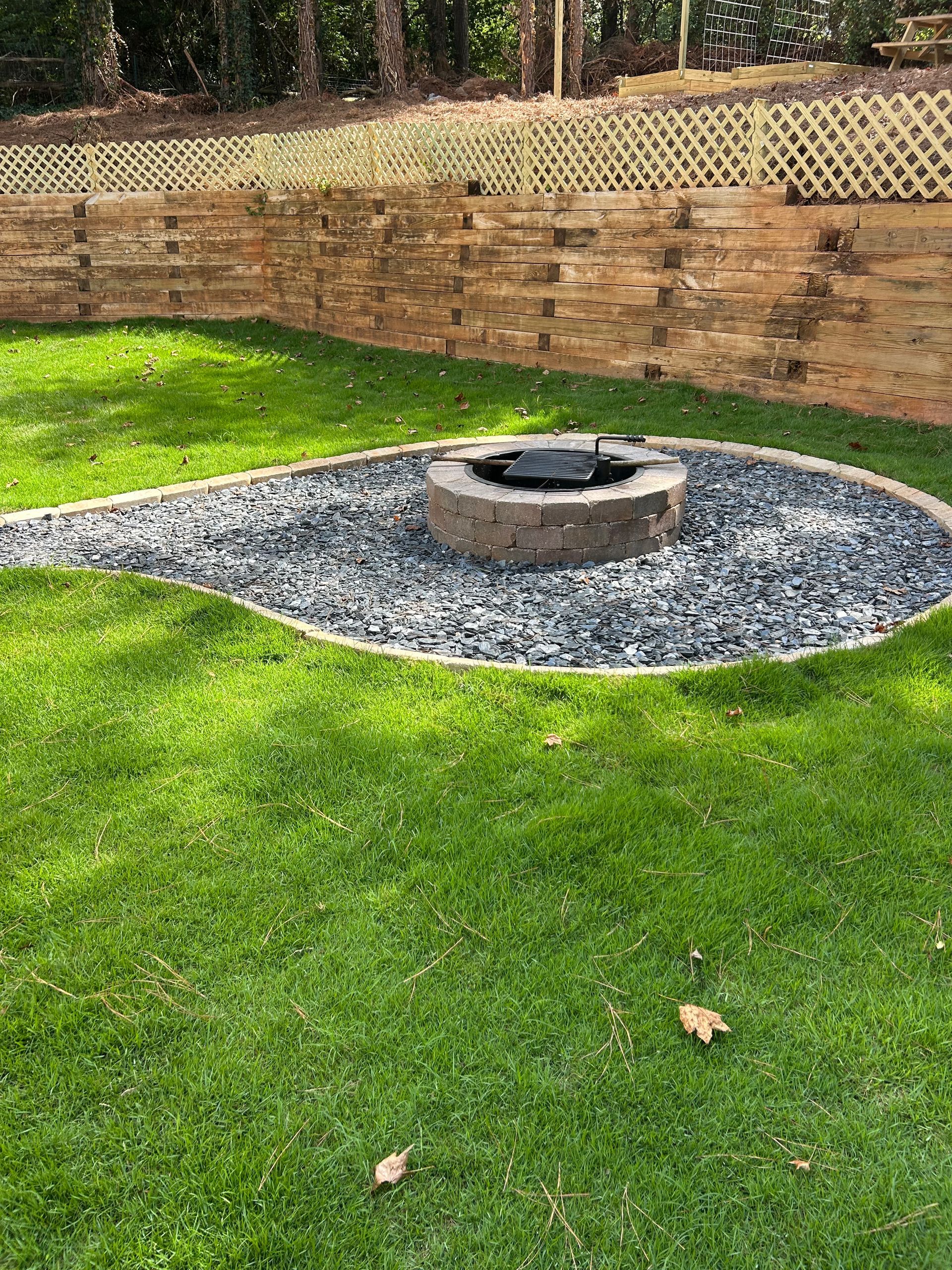 A raised garden bed with stone edging and green shrubs against a beige building.