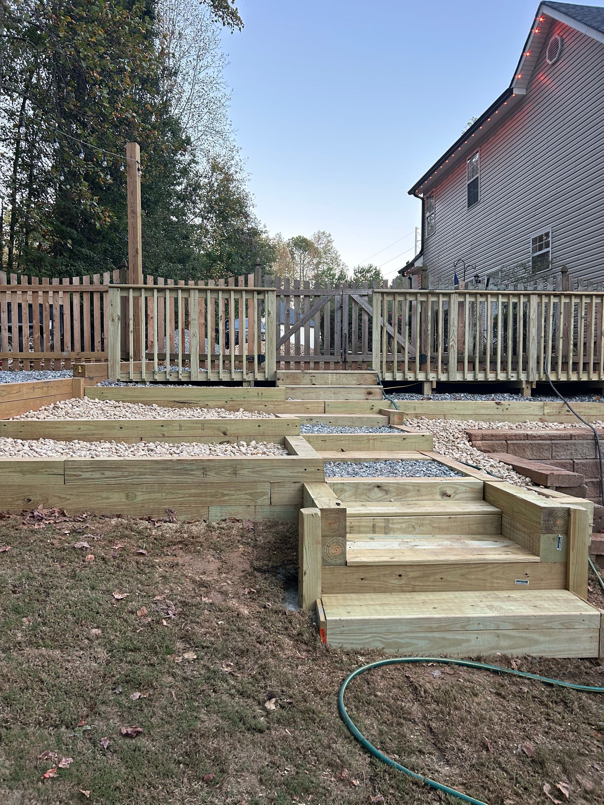 Modern black house with wooden deck, pergola, and outdoor dining set, on a sunny day.