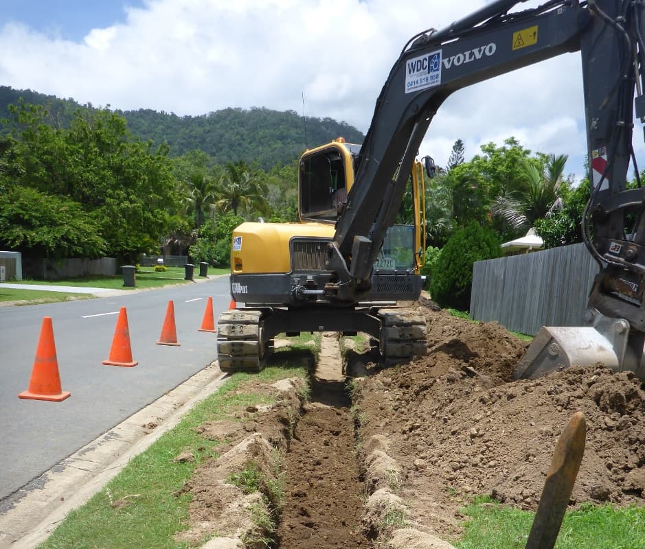 Yellow Excavator Digging Trench — Whitsunday Drainage Contractors in Airlie Beach, QLD