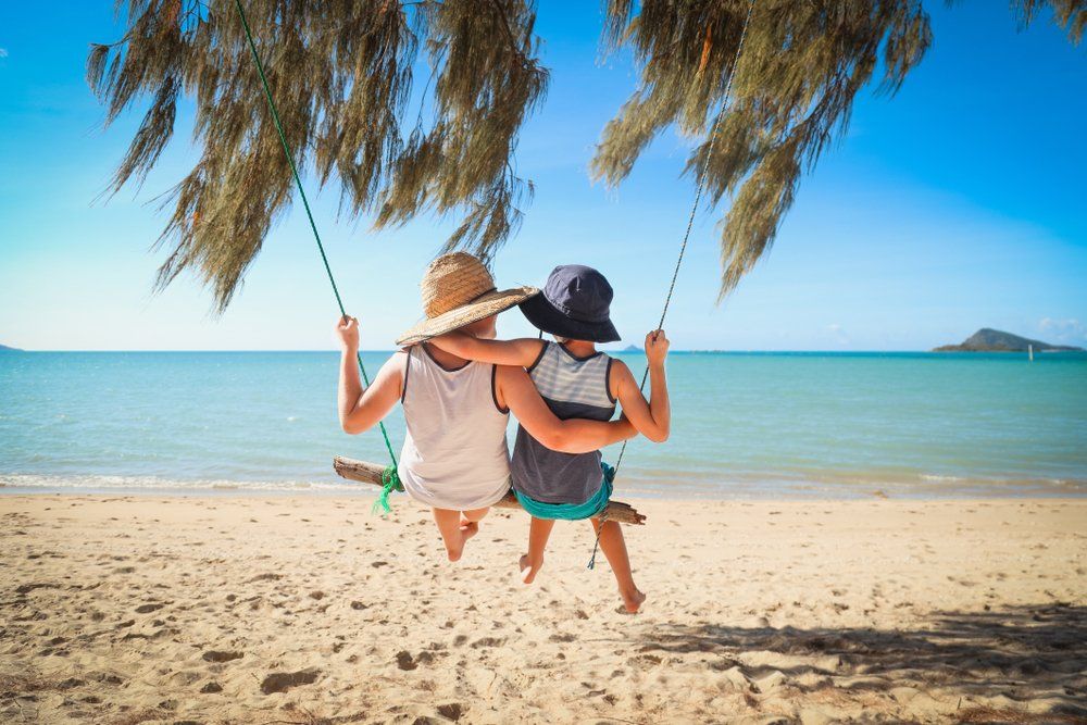 Boys Swinging on Log Swing at Dingo Beach, Near Airlie Beach — Whitsunday Drainage Contractors in Cannonvale, QLD