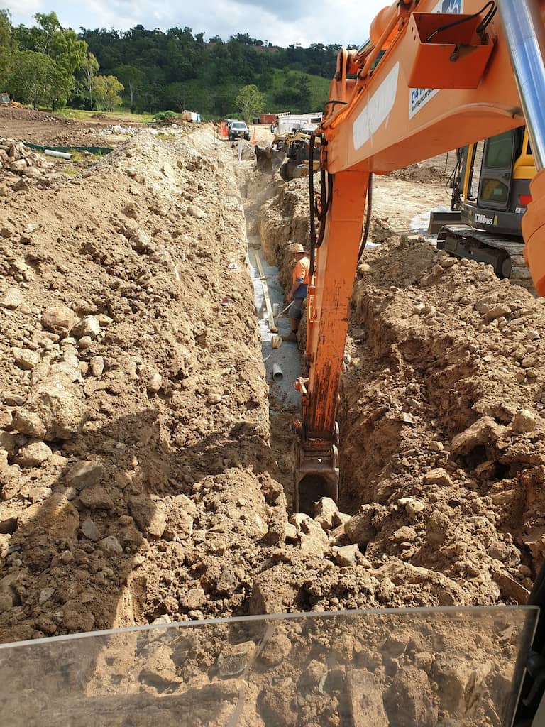 Trench Being Dug By Excavator — Whitsunday Drainage Contractors in Airlie Beach, QLD