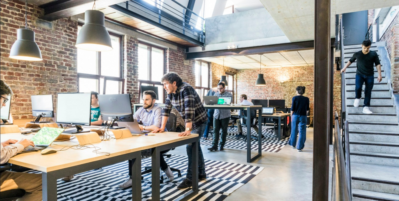 A group of people are sitting at desks in an office.