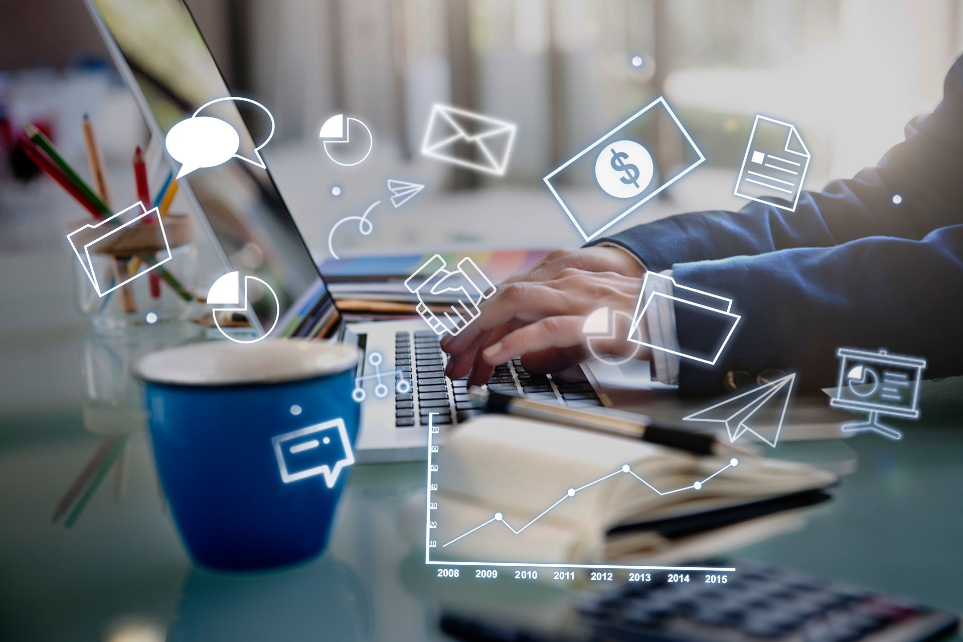 Person typing on a laptop at a desk with floating digital icons.