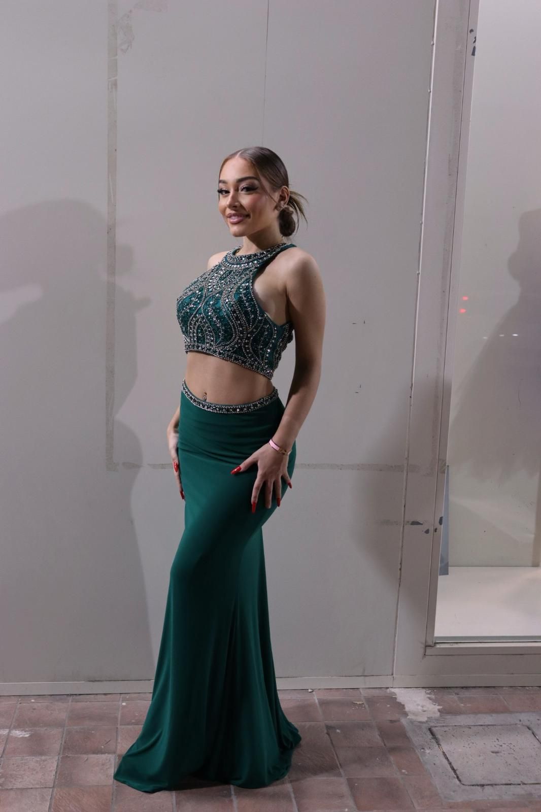 Una donna con un vestito verde è in piedi davanti a un muro.