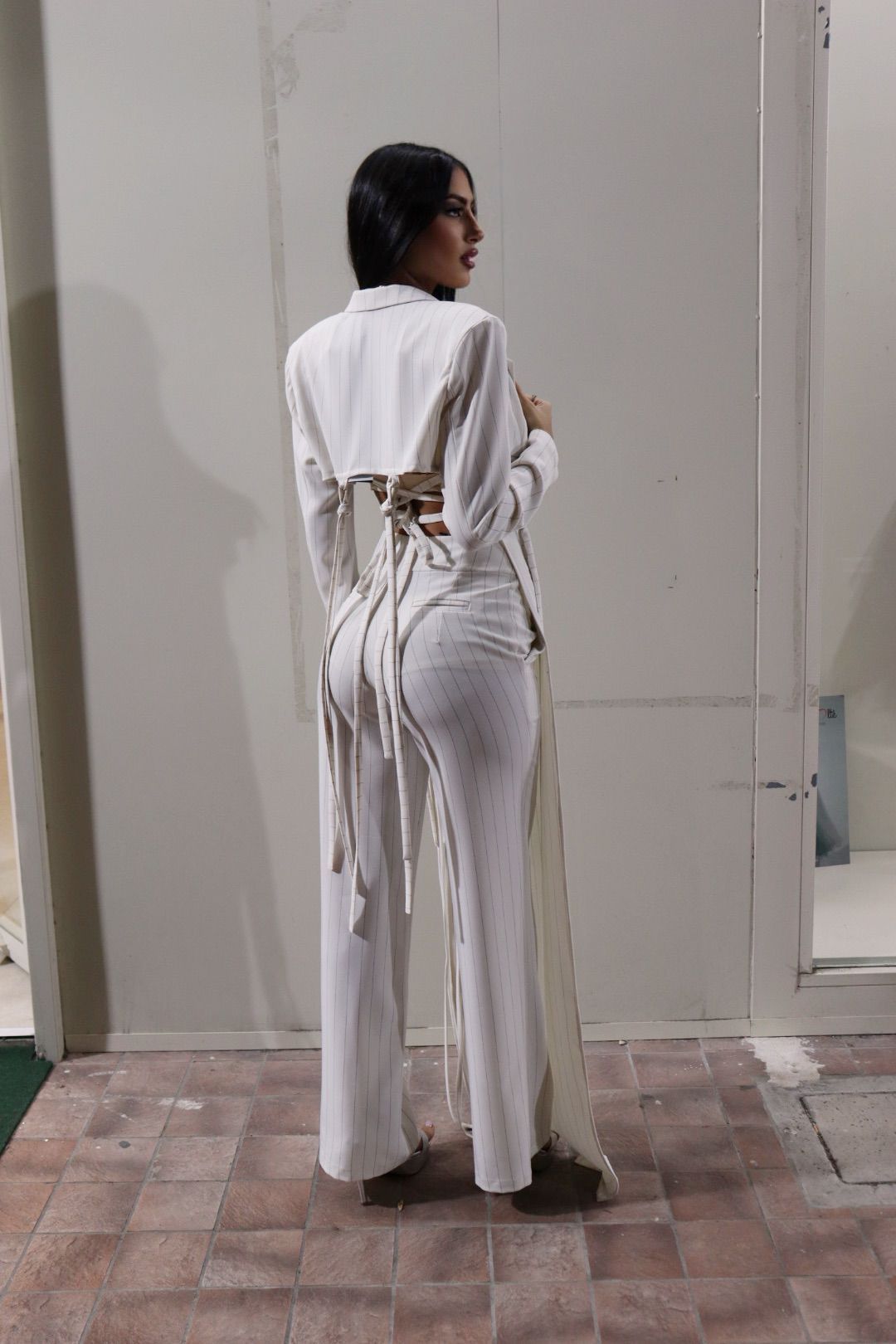 Una donna in abito bianco è in piedi davanti a un edificio.