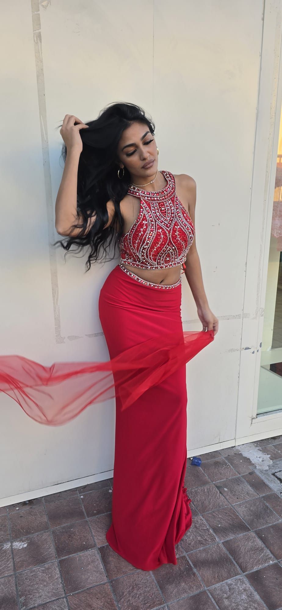 Una donna con un vestito rosso è in piedi davanti a un muro bianco.