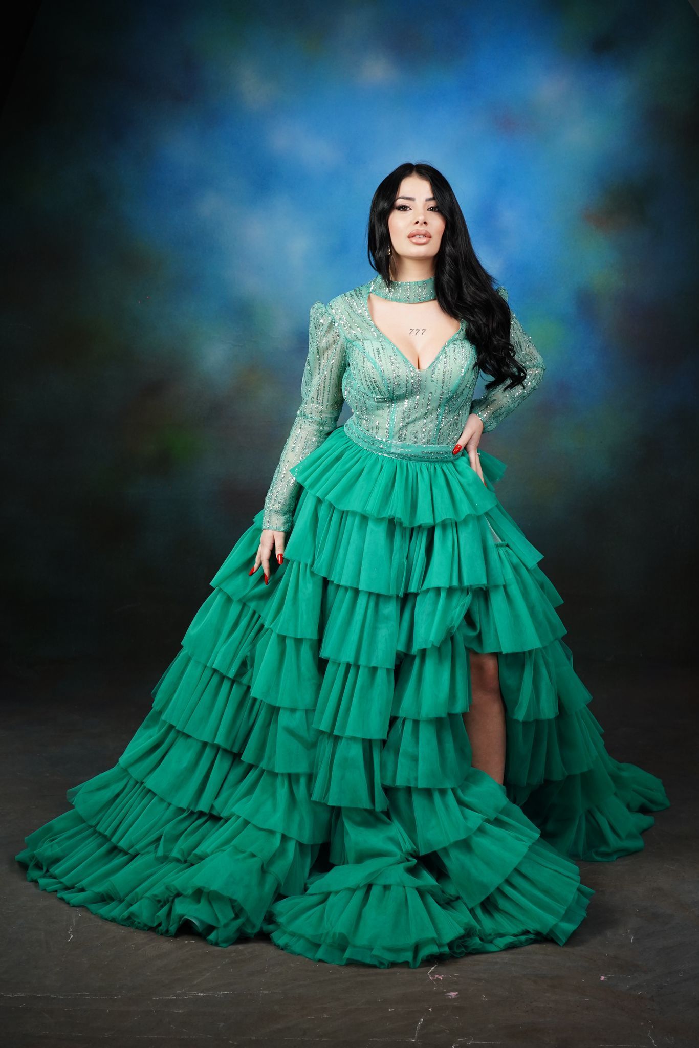 Una donna con un vestito verde con volant è in piedi davanti a uno sfondo blu.