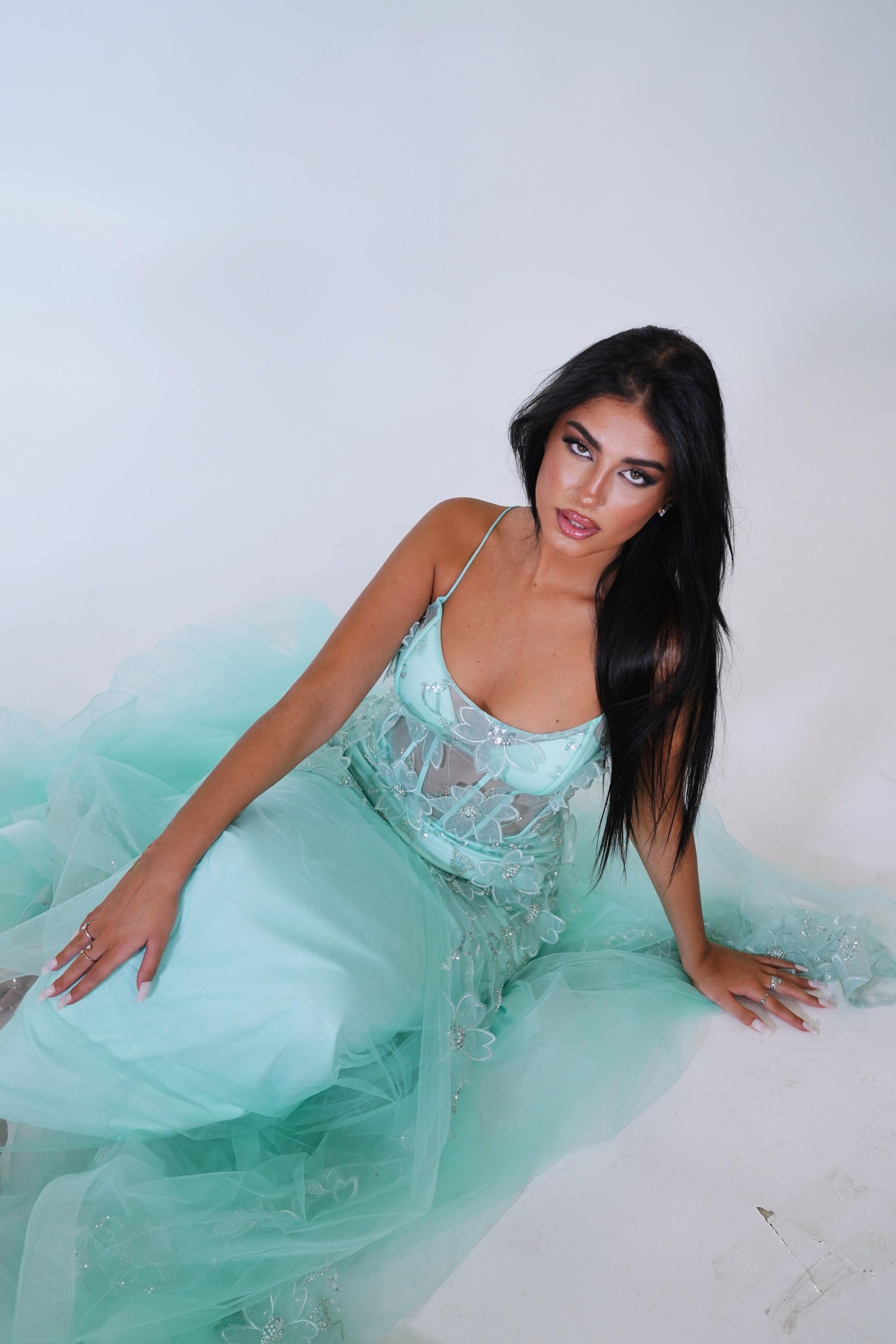 Una donna con un vestito verde è seduta sul pavimento.