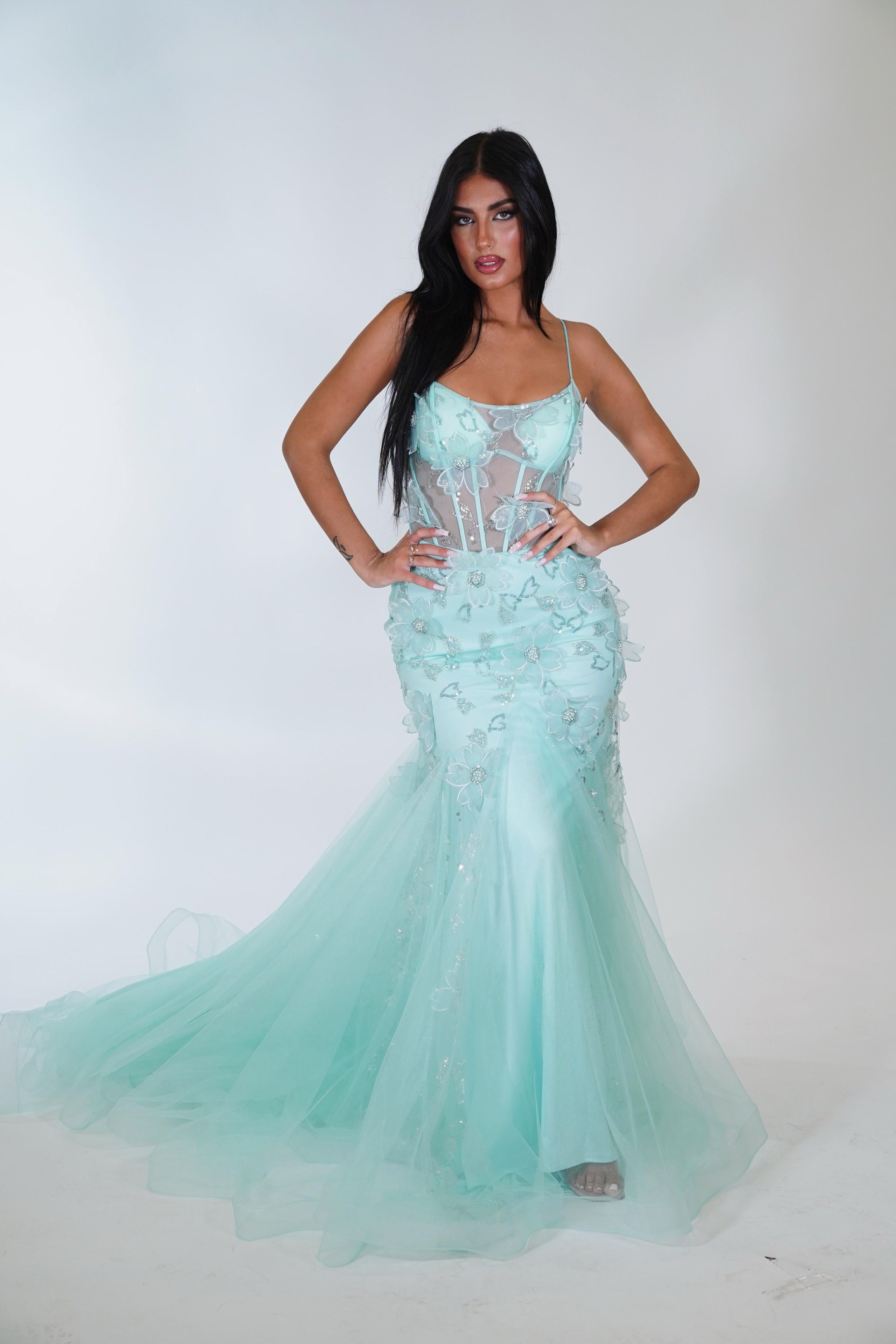 Una donna è in piedi con un lungo abito verde menta.