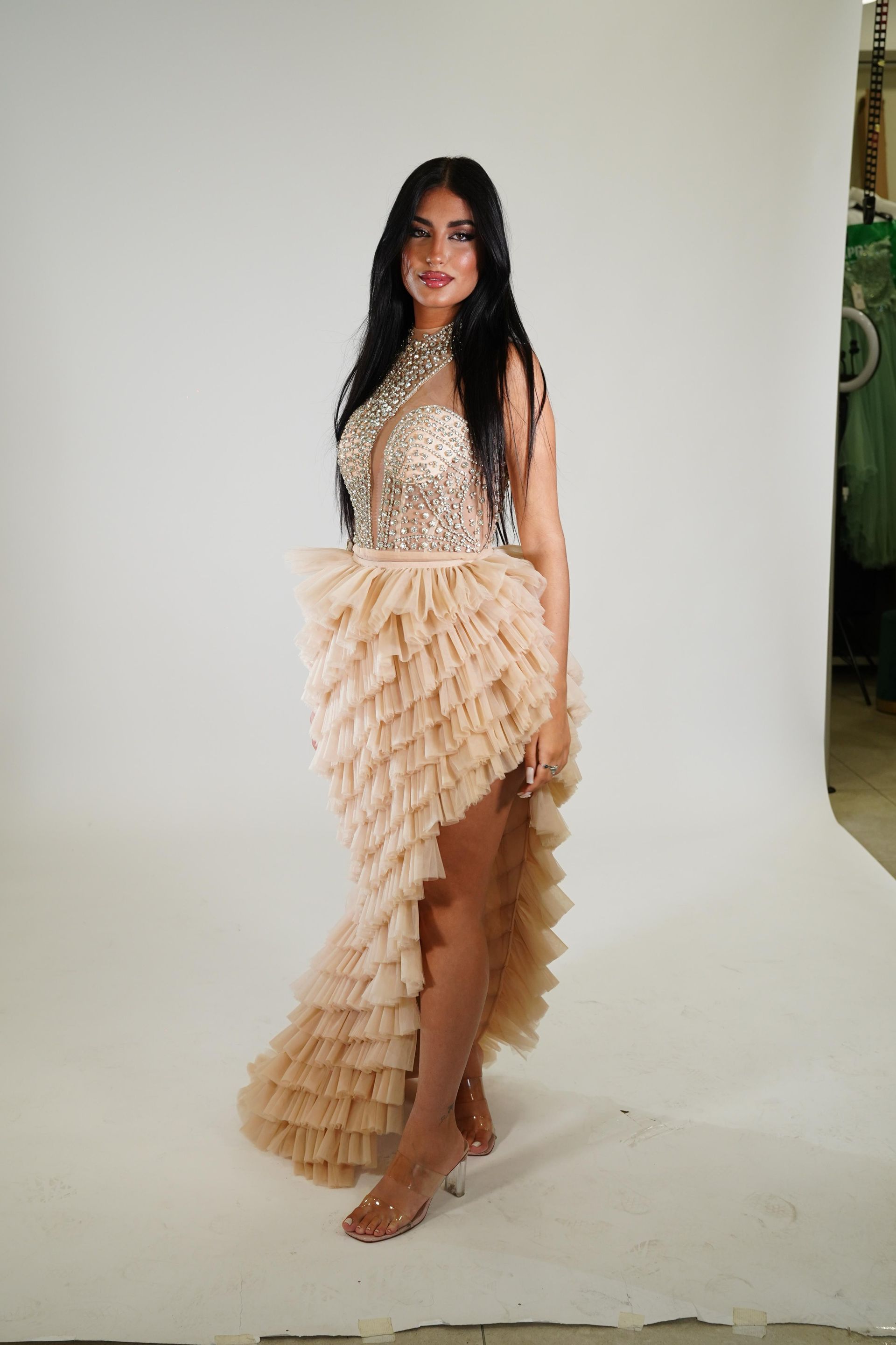 Una donna con un abito asimmetrico è in piedi davanti a un muro bianco.