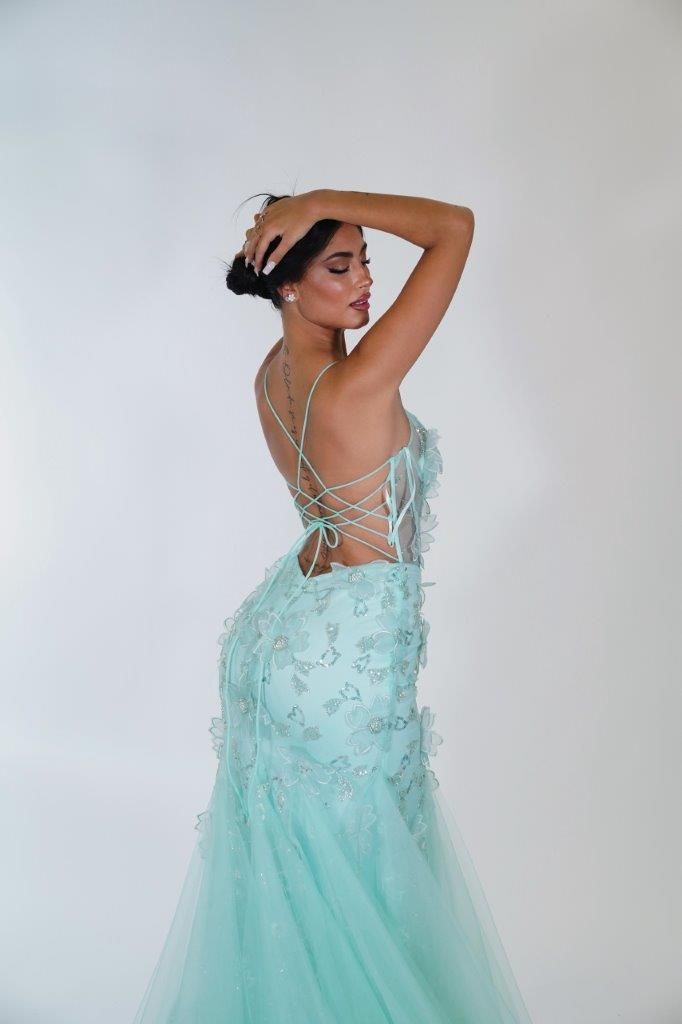 Una donna con un vestito verde menta è in piedi con la mano sulla testa.