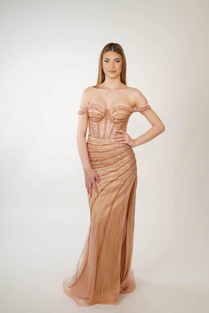 Una donna con un lungo abito è in piedi davanti a uno sfondo bianco.