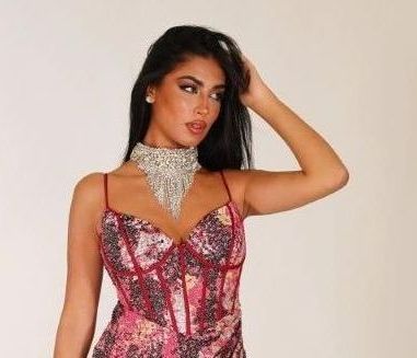 Una donna indossa un vestito rosa e una collana.