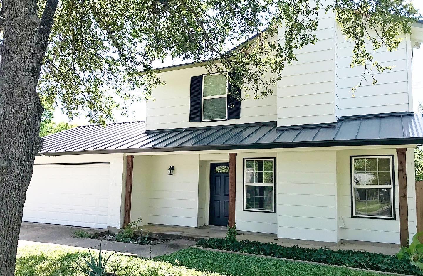 Two-story white house with a garage and front porch under a leafy tree