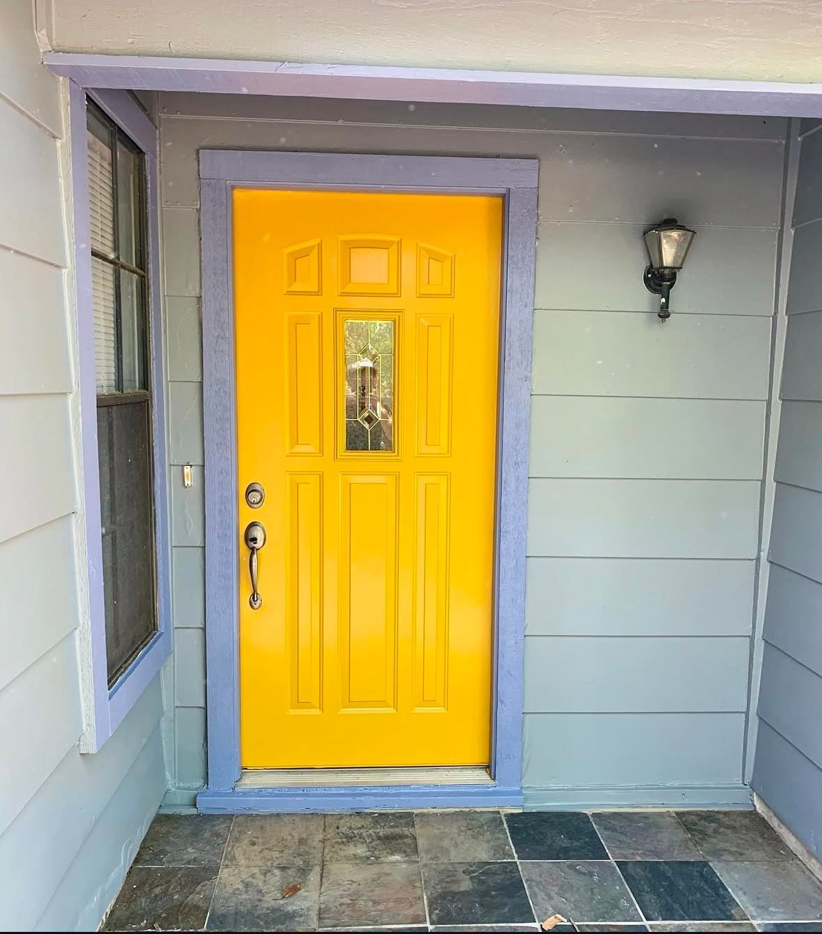 Yellow front door with blue trim and gray siding.